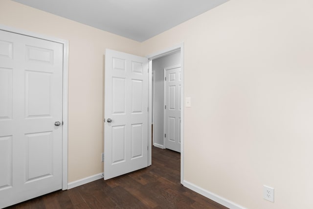 unfurnished bedroom featuring baseboards and dark wood-type flooring