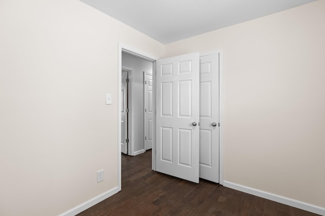 unfurnished bedroom featuring baseboards and dark wood-style flooring