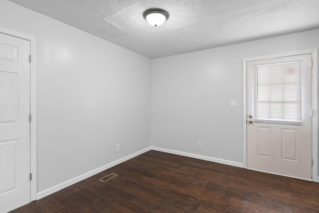 empty room featuring visible vents, a textured ceiling, baseboards, and wood finished floors