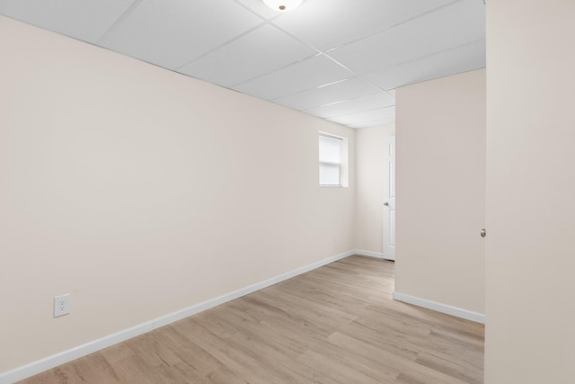 unfurnished room featuring light wood finished floors, baseboards, and a drop ceiling