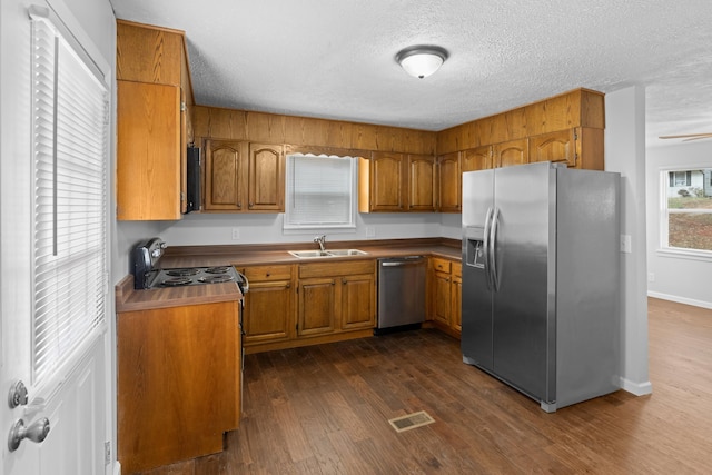 kitchen featuring a sink, brown cabinets, dark wood-type flooring, and appliances with stainless steel finishes