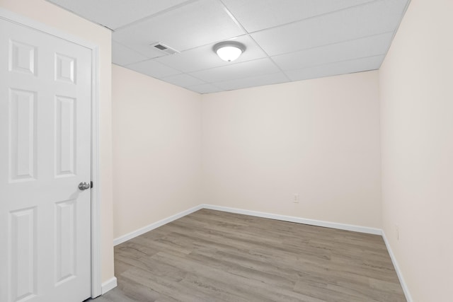 empty room featuring visible vents, a paneled ceiling, baseboards, and wood finished floors