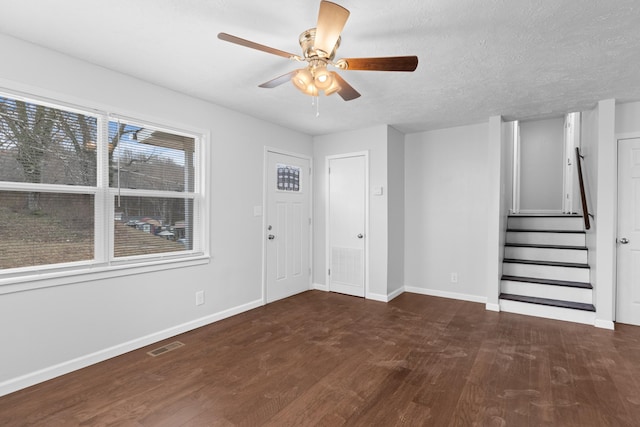 foyer entrance featuring visible vents, a textured ceiling, wood finished floors, baseboards, and stairs