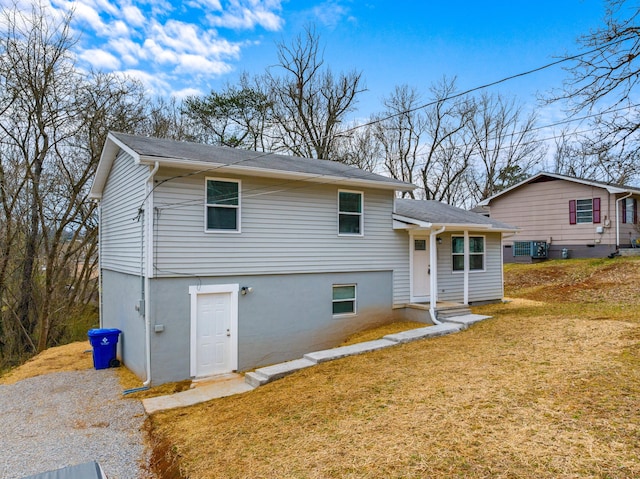 tri-level home with a front yard, central air condition unit, and stucco siding