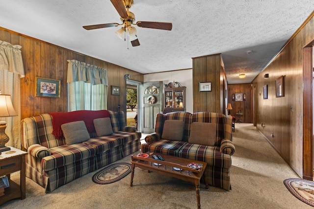 carpeted living room with a textured ceiling, ceiling fan, and wood walls