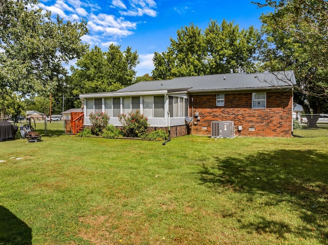 back of house featuring central air condition unit, a yard, and a sunroom