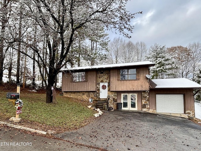 split foyer home with driveway, an attached garage, entry steps, french doors, and stone siding