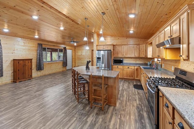 kitchen with hanging light fixtures, light stone counters, a center island, and stainless steel appliances