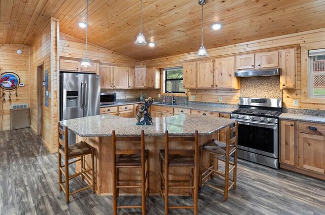 kitchen with a breakfast bar area, a kitchen island, hanging light fixtures, and appliances with stainless steel finishes