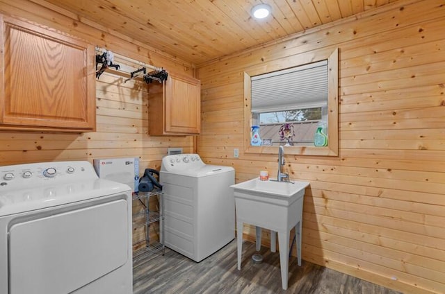 clothes washing area with washing machine and clothes dryer, wooden walls, dark wood-type flooring, and cabinets