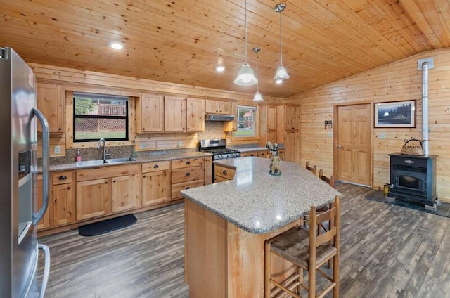 kitchen with sink, hanging light fixtures, vaulted ceiling, light stone counters, and stainless steel appliances