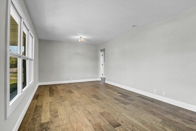 spare room with wood finished floors, a textured ceiling, and baseboards