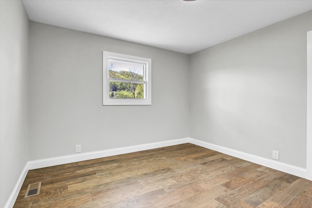 spare room with baseboards, wood finished floors, and visible vents