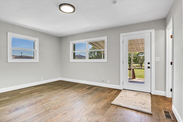 doorway with baseboards, wood finished floors, and visible vents
