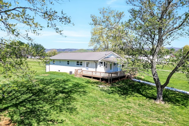rear view of house featuring a lawn and a deck with mountain view