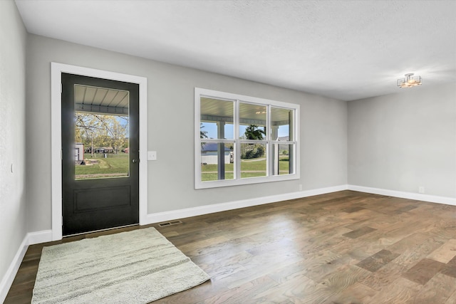 foyer entrance featuring baseboards, visible vents, and dark wood finished floors
