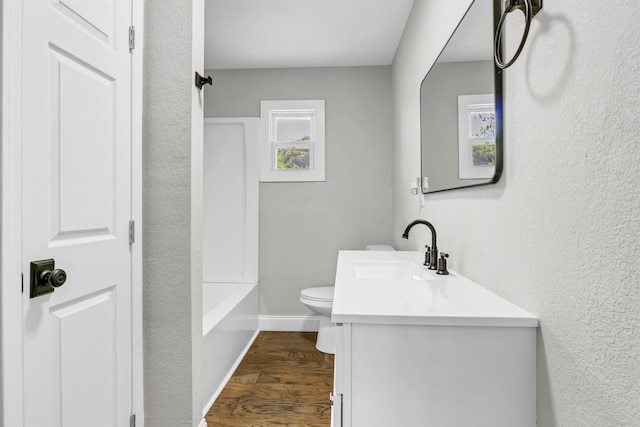 full bathroom with toilet, walk in shower, wood finished floors, vanity, and a tub