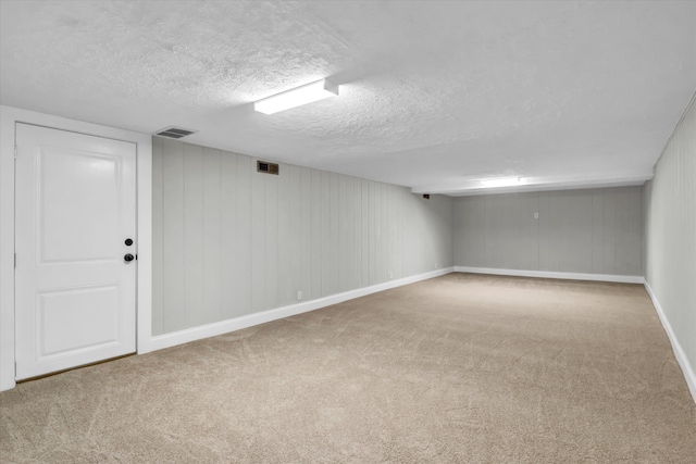 finished below grade area featuring baseboards, visible vents, carpet floors, and a textured ceiling