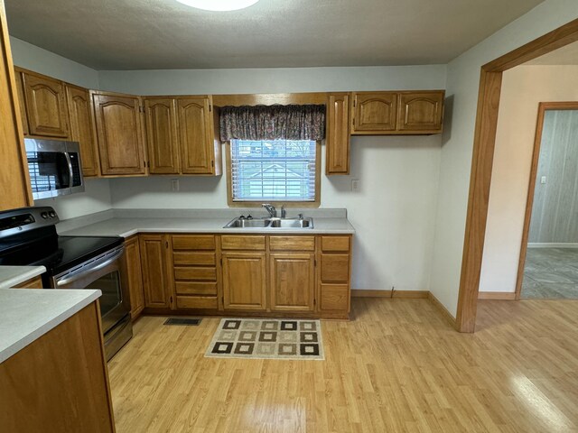 kitchen featuring appliances with stainless steel finishes, light wood-type flooring, and sink