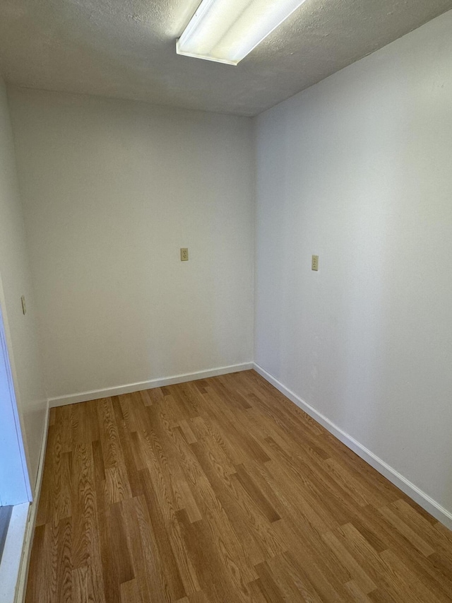 empty room featuring a textured ceiling and light hardwood / wood-style flooring