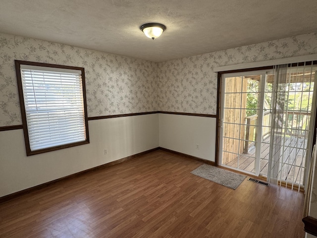 unfurnished room with a textured ceiling and dark wood-type flooring