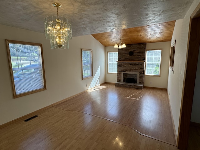 unfurnished living room with wood ceiling, hardwood / wood-style flooring, a chandelier, and a brick fireplace