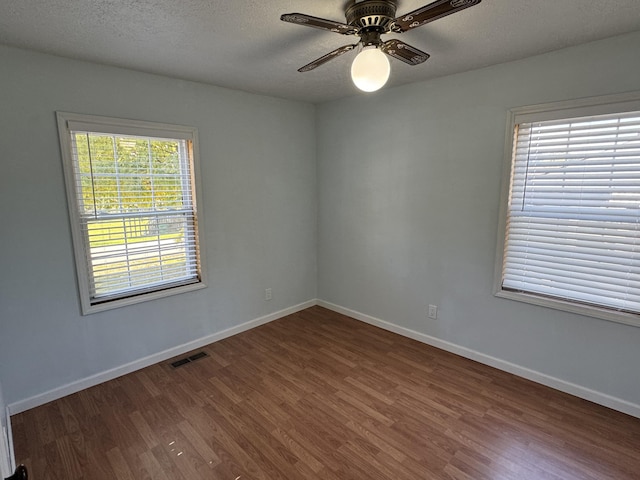 spare room featuring dark hardwood / wood-style floors, ceiling fan, and plenty of natural light