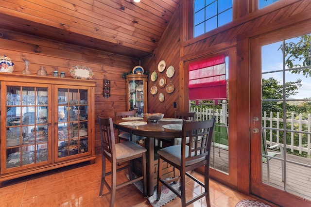 tiled dining space with wood walls, wooden ceiling, high vaulted ceiling, and french doors