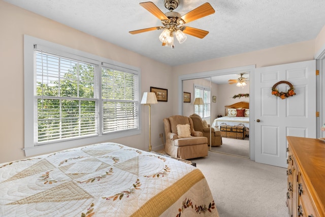 carpeted bedroom with ceiling fan, a textured ceiling, and a closet