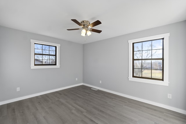 unfurnished room featuring a wealth of natural light, dark hardwood / wood-style floors, and ceiling fan