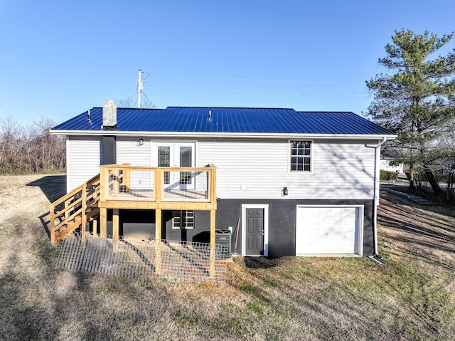 rear view of property with a wooden deck and a garage