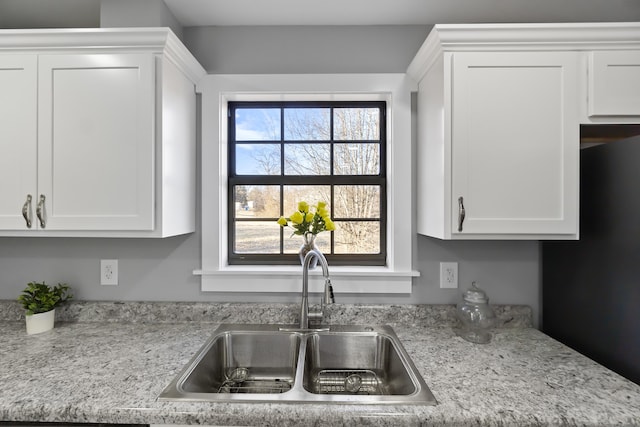 kitchen featuring white cabinetry, sink, and light stone counters