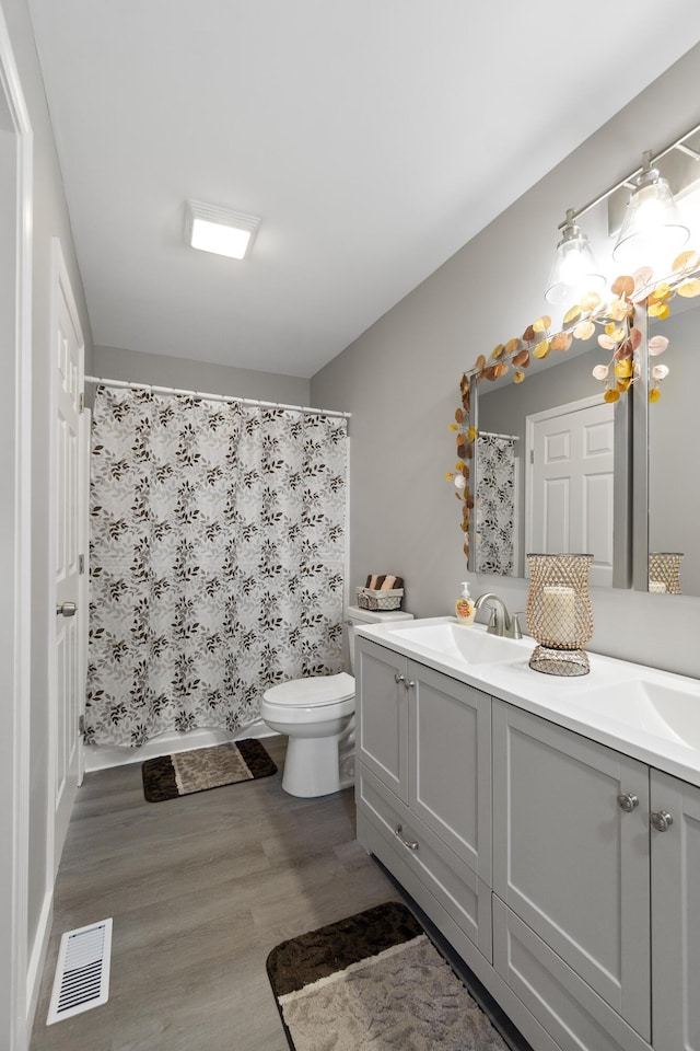 bathroom with a chandelier, hardwood / wood-style flooring, vanity, walk in shower, and toilet