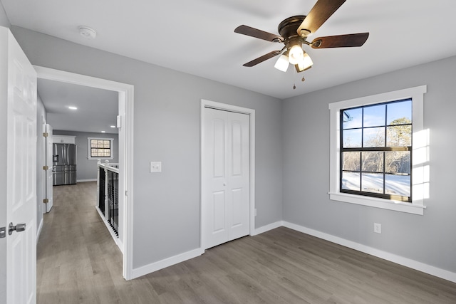 unfurnished bedroom featuring stainless steel fridge with ice dispenser, a closet, ceiling fan, and light wood-type flooring