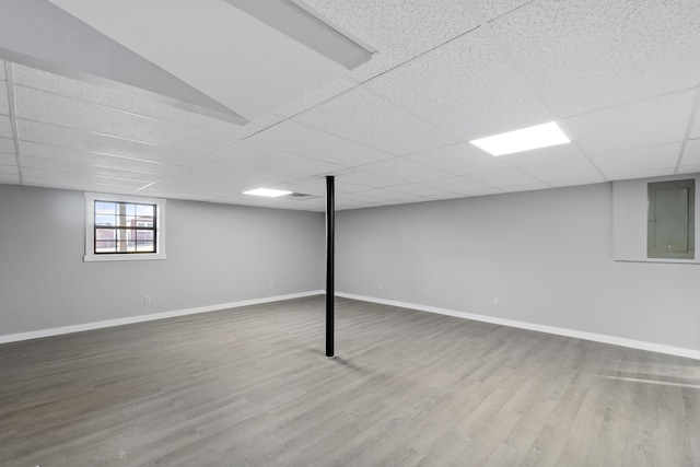 basement with hardwood / wood-style flooring, a paneled ceiling, and electric panel