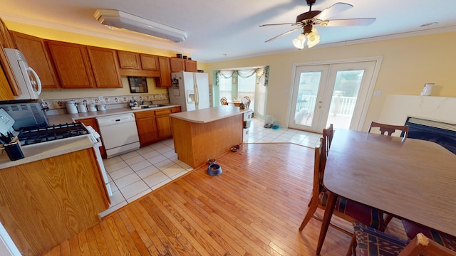 kitchen featuring french doors, white appliances, a healthy amount of sunlight, sink, and a kitchen island