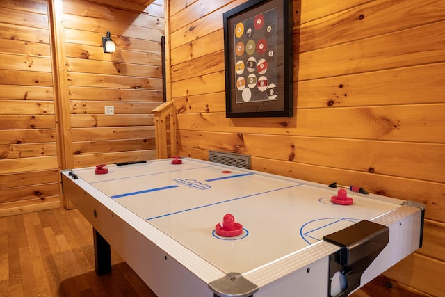 rec room with light wood-type flooring and wooden walls