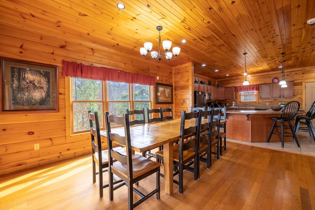 dining space with wood ceiling, wooden walls, light wood-type flooring, and an inviting chandelier