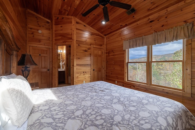 bedroom featuring wood walls, wooden ceiling, ensuite bathroom, vaulted ceiling, and ceiling fan