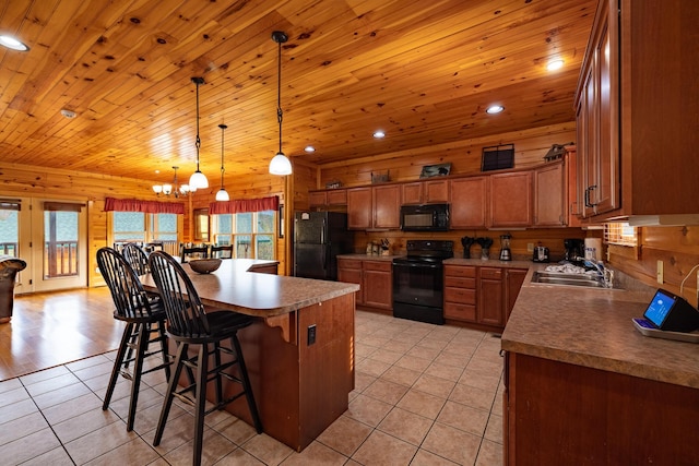 kitchen with black appliances, sink, hanging light fixtures, light tile patterned flooring, and a kitchen bar