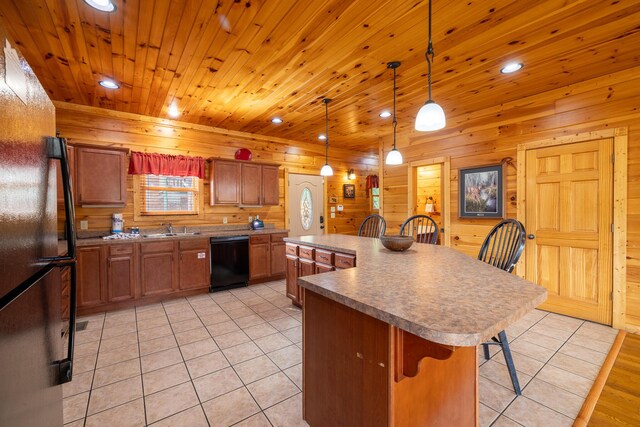 kitchen with black appliances, wooden walls, decorative light fixtures, a kitchen island, and a kitchen bar