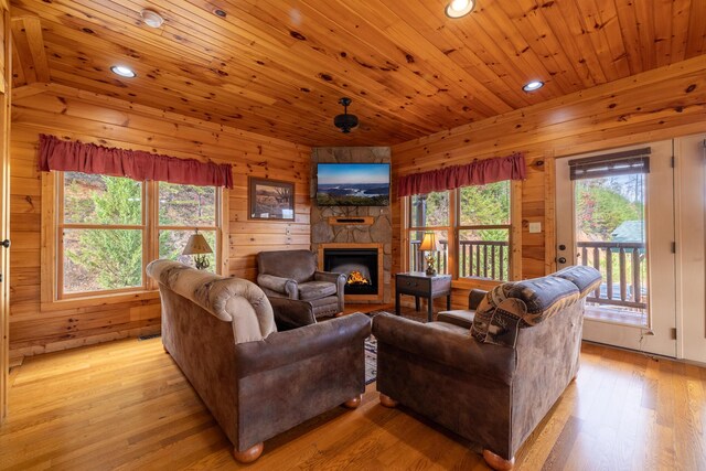 living room featuring light hardwood / wood-style floors, wooden ceiling, a fireplace, and a wealth of natural light