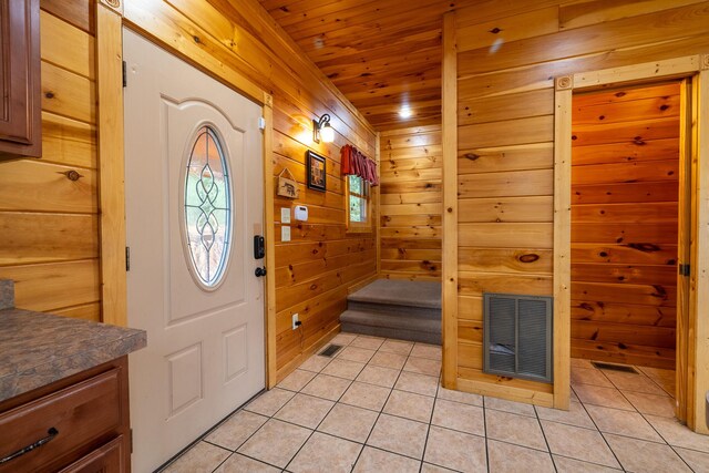 tiled foyer entrance featuring wood walls and wood ceiling