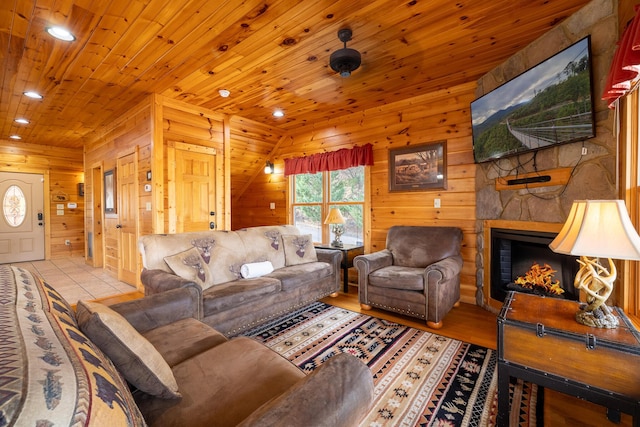 living room featuring a stone fireplace, wooden walls, and wooden ceiling