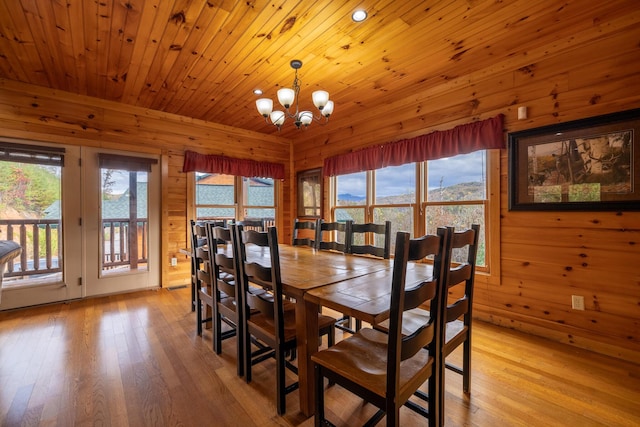 dining room featuring a chandelier, light wood-type flooring, wooden walls, and wood ceiling