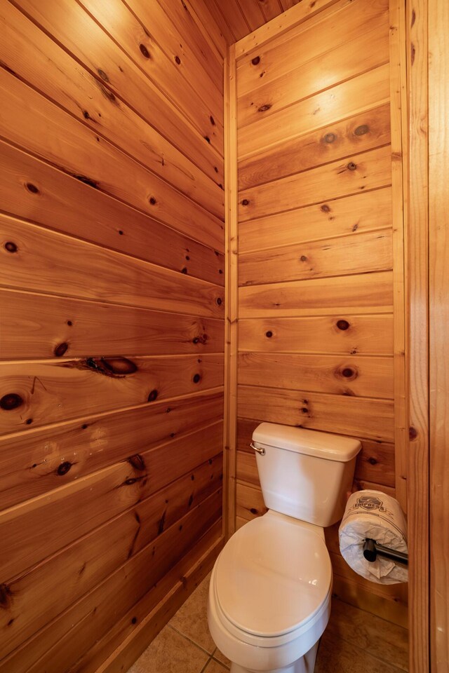 bathroom featuring tile patterned floors, toilet, and wooden walls