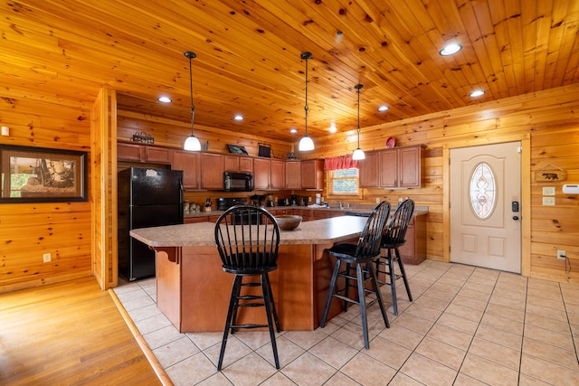 kitchen with black appliances, a center island, pendant lighting, and light tile patterned floors