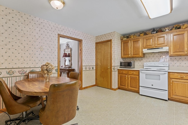 10741 Rutledge Pike, Blaine, TN 37709 - kitchen with white electric range, stainless steel microwave, wallpapered walls, under cabinet range hood, and light countertops