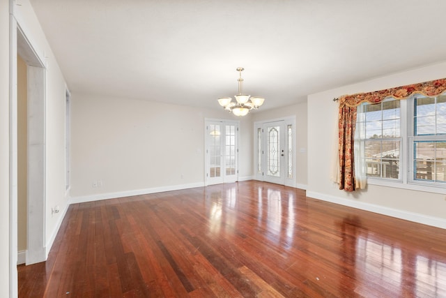 empty room with baseboards, hardwood / wood-style floors, and an inviting chandelier