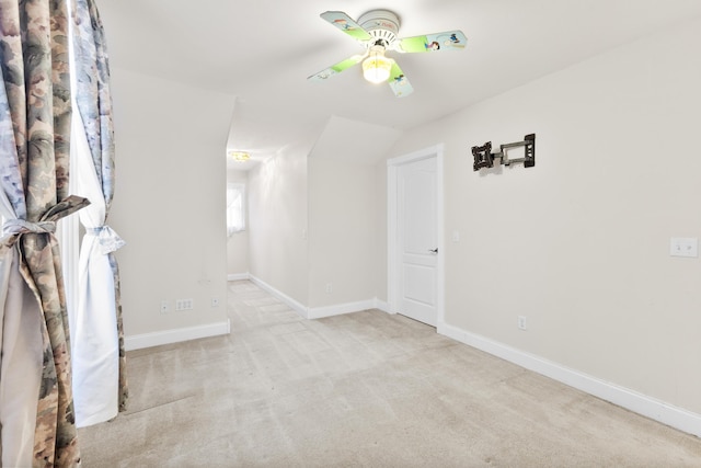 carpeted spare room with lofted ceiling, ceiling fan, and baseboards